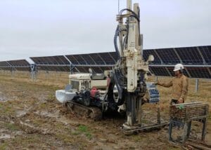 testing tech running CPT machinery on site with solar panels in background