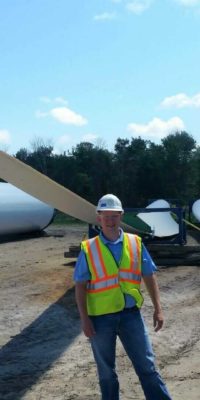 MTC employee in front of wind farm turbine