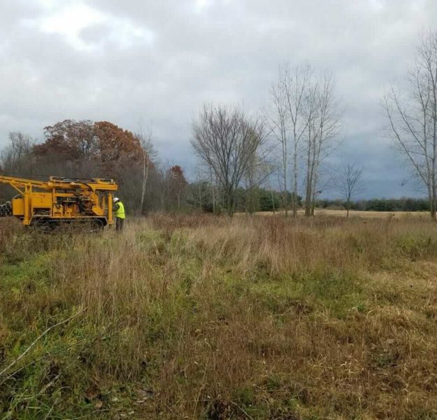 Employee prepping for drill rig setup to assess a future job site for environmental compliance