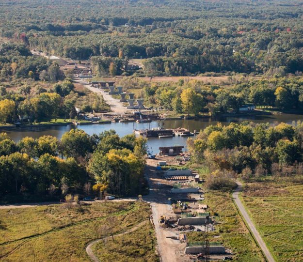 Aerial view of barge and crane performing geotechnical services for US-231 bridge construction in Ottawa County, Michigan.