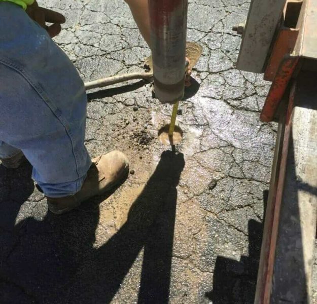 Technician obtaining a core sample of asphalt and subgrade as part of a pavement management project.